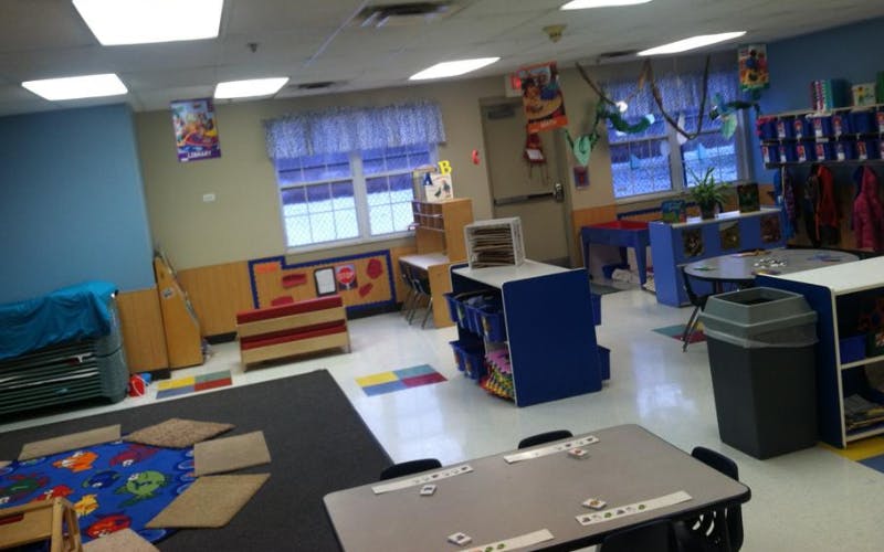 Empty classroom with small tables, chairs, and play areas