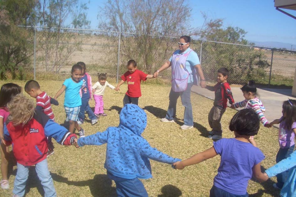 Adult and children holding hands in a circle outdoors