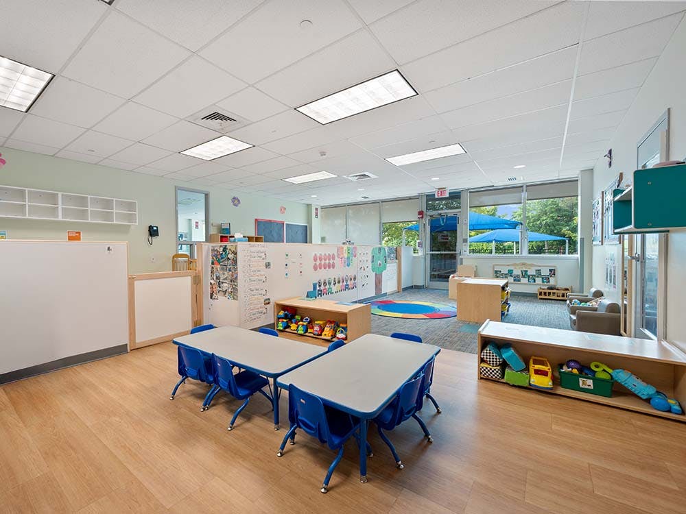 An empty preschool classroom with tables, chairs, and toys