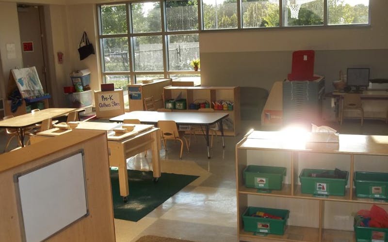 Classroom with tables, chairs, bookshelves, and a window looking outdoors