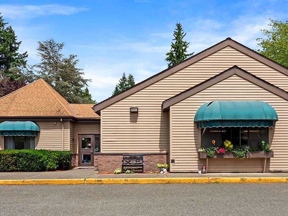 Building with beige siding and two green awnings
