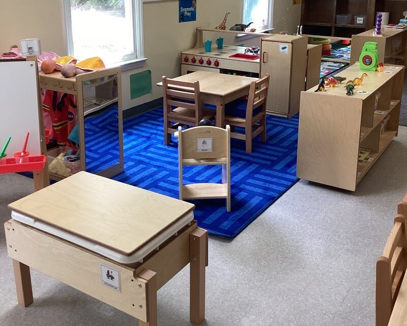 Classroom with child-sized furniture and a blue patterned rug