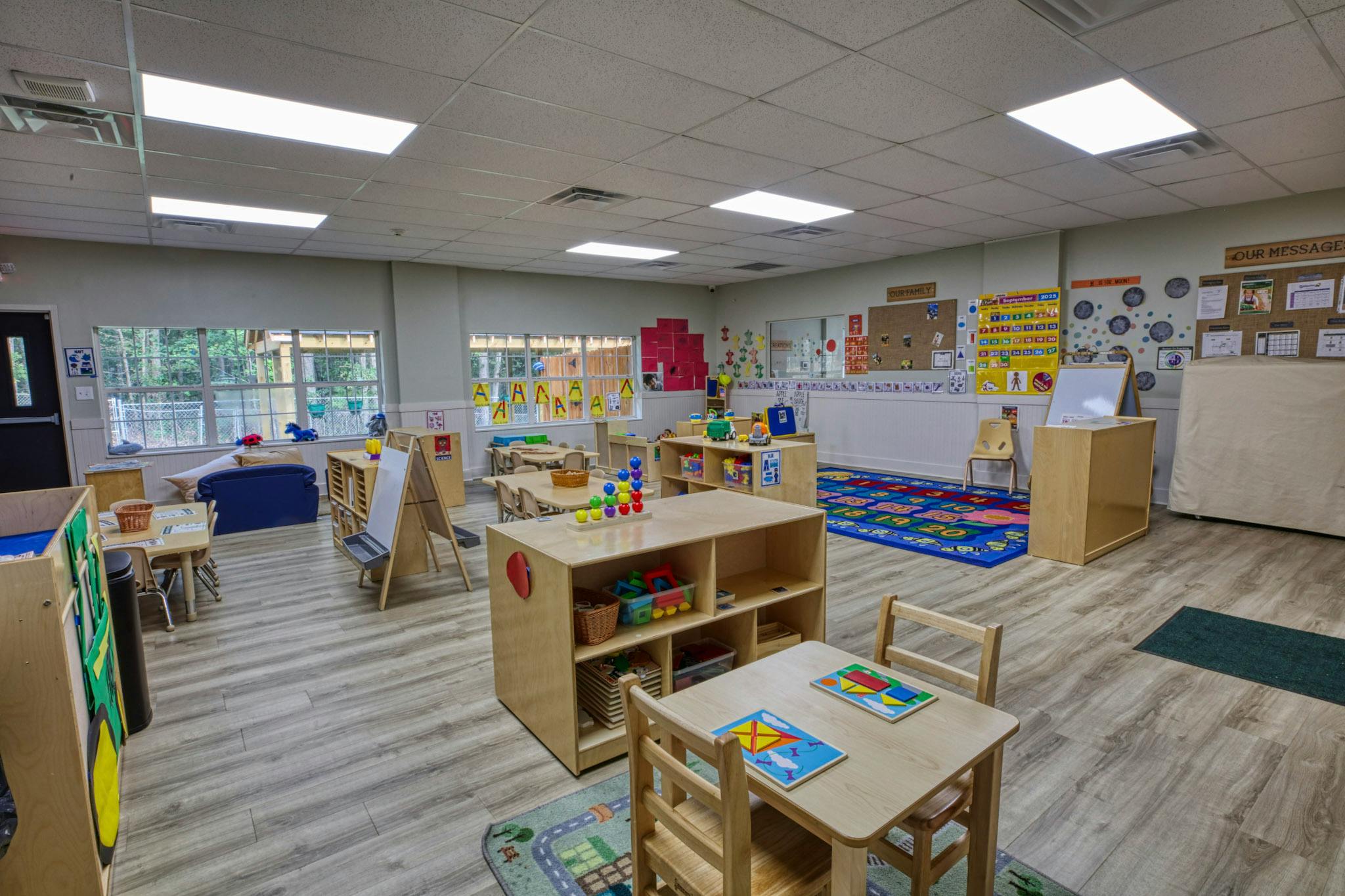 A colorful and organized preschool classroom with small tables and learning materials