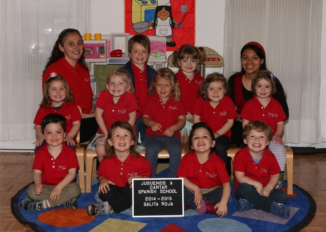 Two adults and multiple children in red shirts posing for a group photo