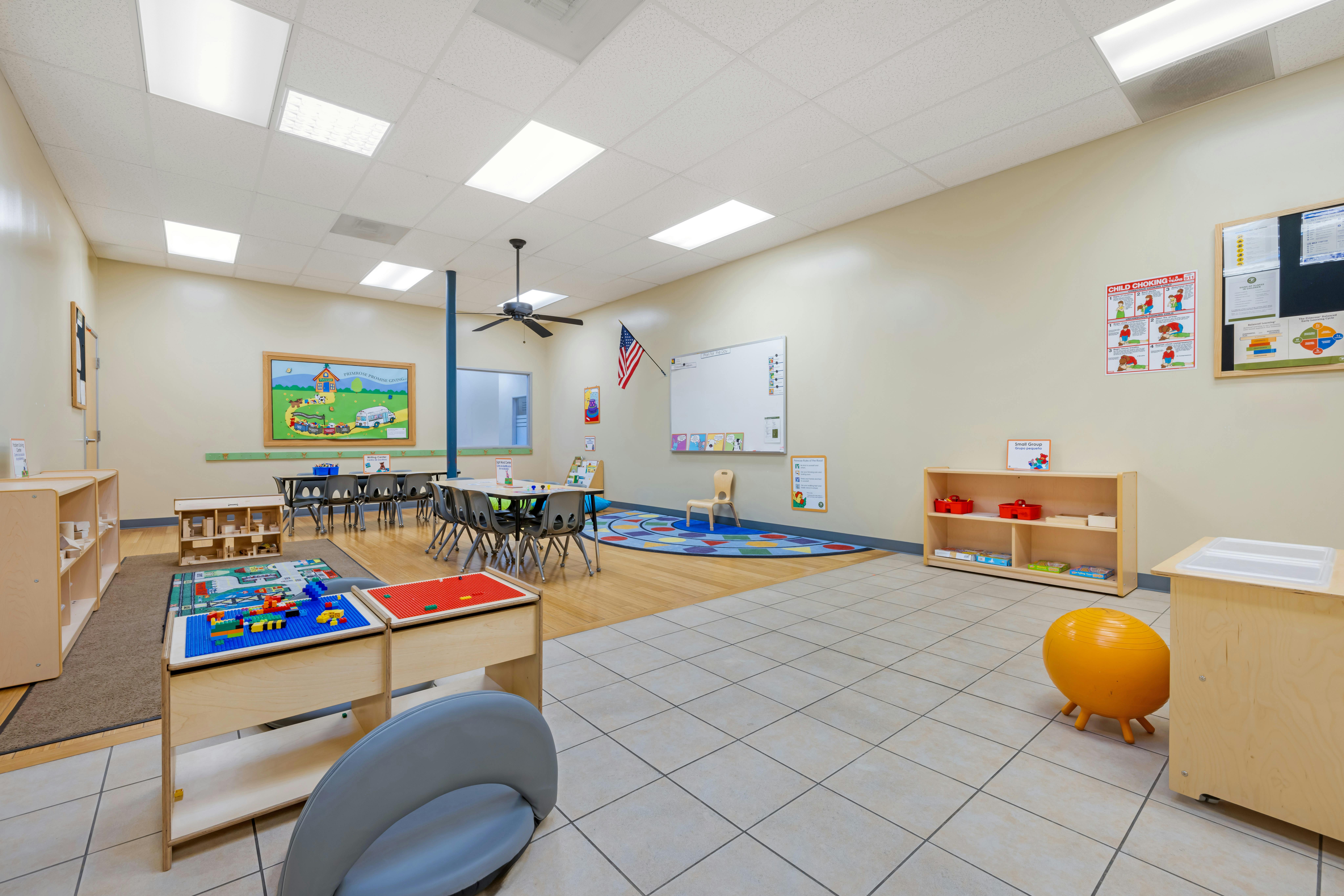 Classroom with tables, chairs, colorful rug, and play areas