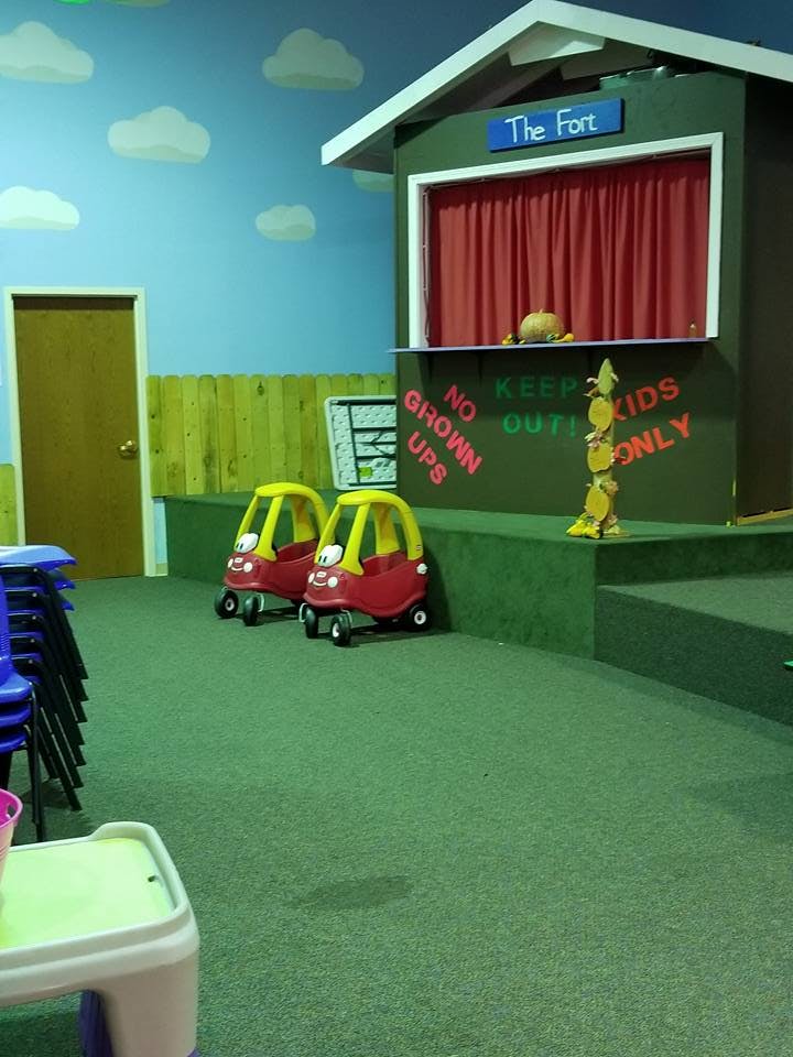 Two toy cars in a play area with a stage labeled "The Fort"