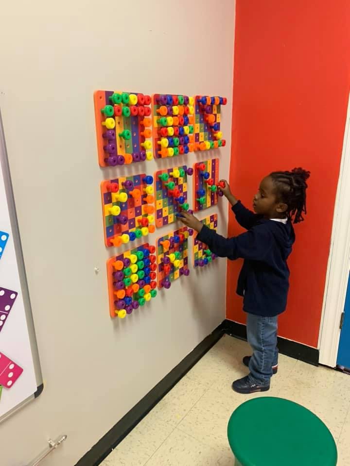 Child playing with colorful wall-mounted blocks in a room
