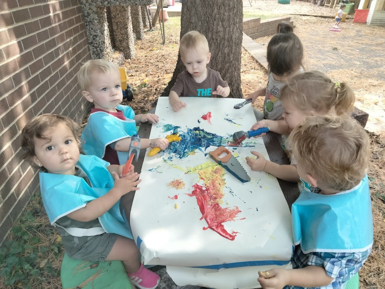 Children painting at a table outdoors