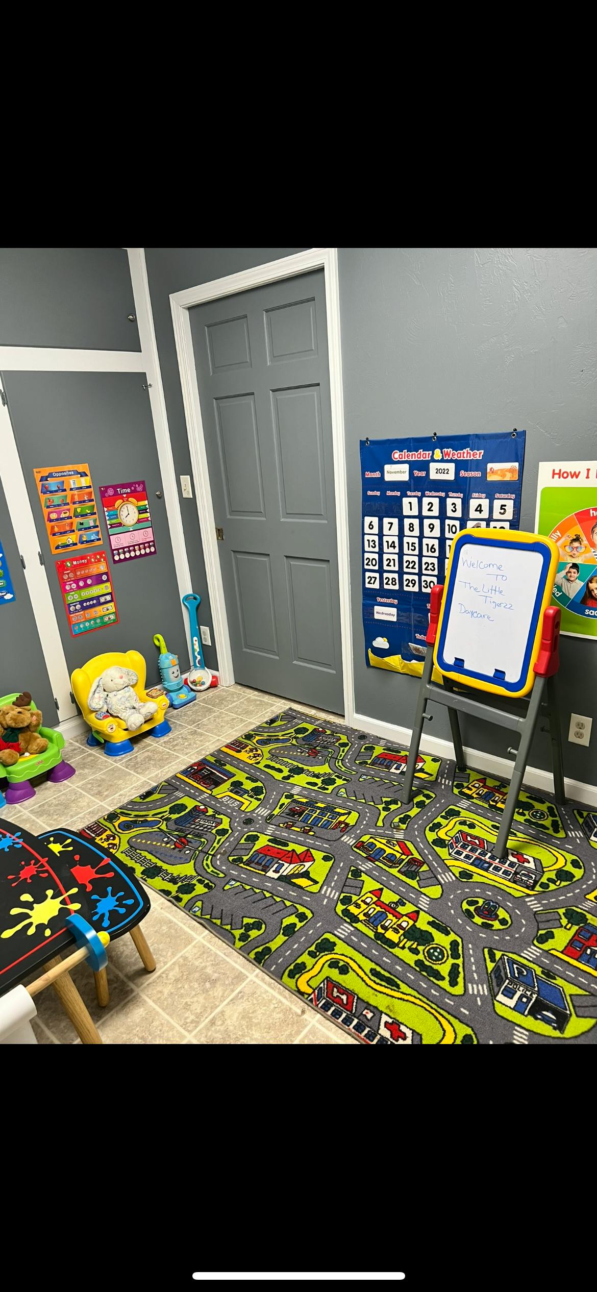 Playroom with a road map rug, small easel, and wall charts