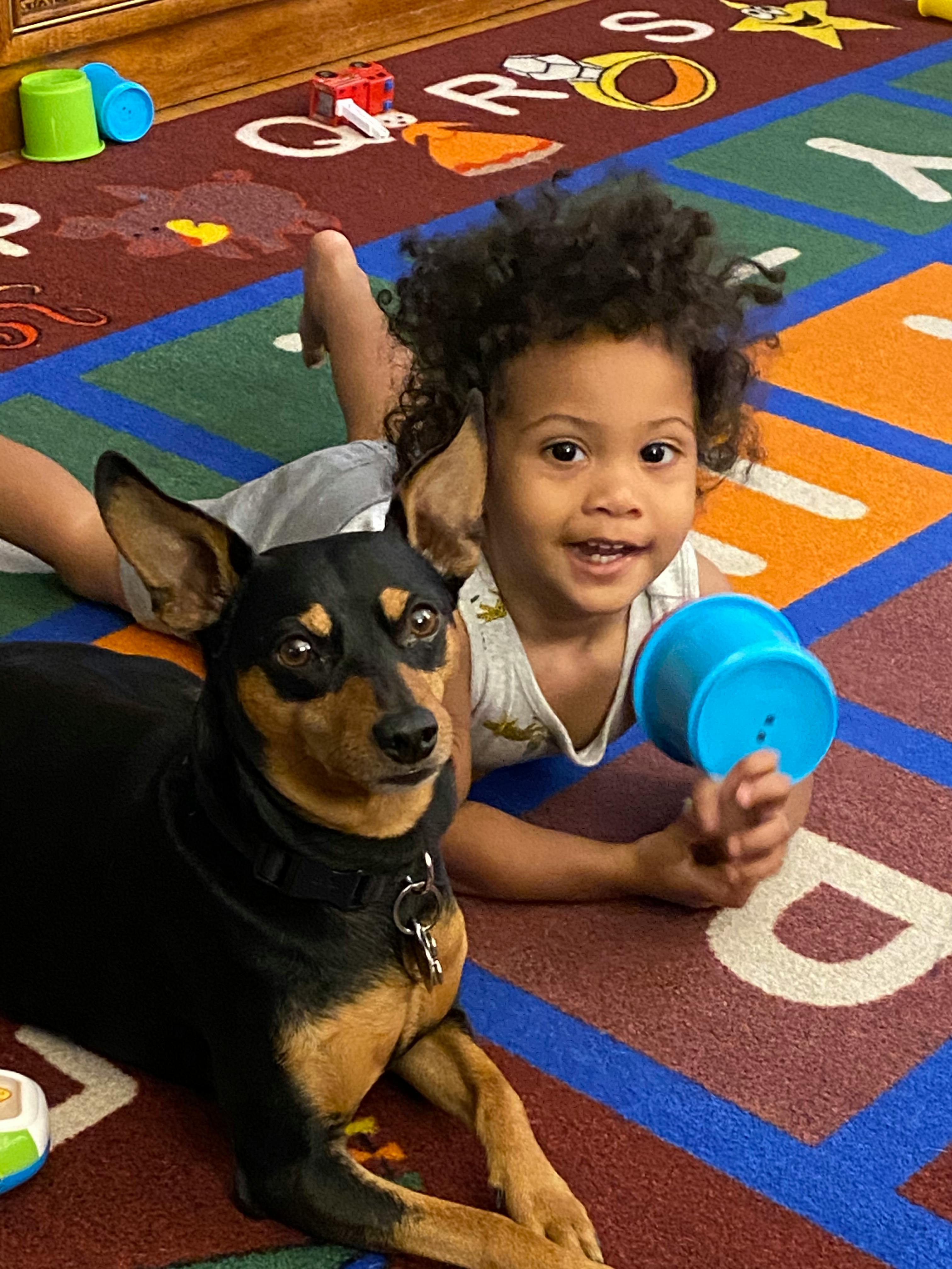 Child and dog lying on a colorful alphabet rug