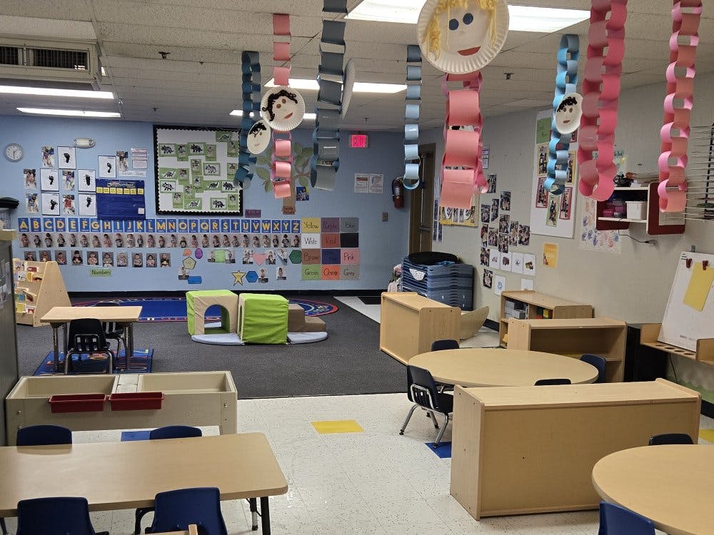 An empty early childhood classroom with small tables and chairs