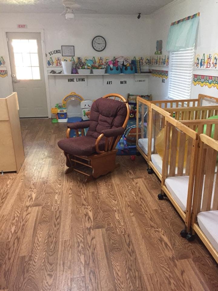 Nursery room with cribs, a rocking chair, and shelves with toys