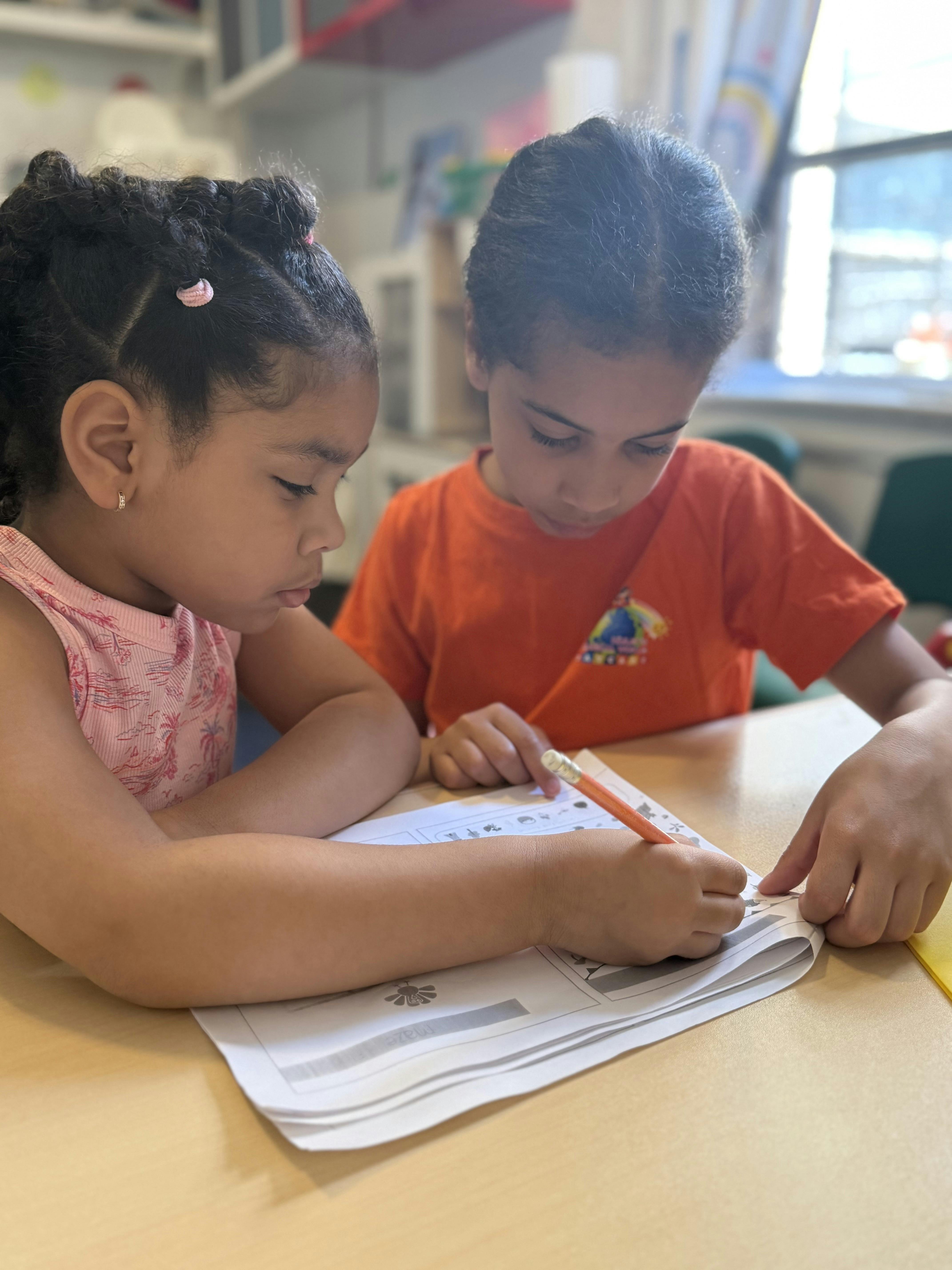Two children working together on a worksheet at a desk