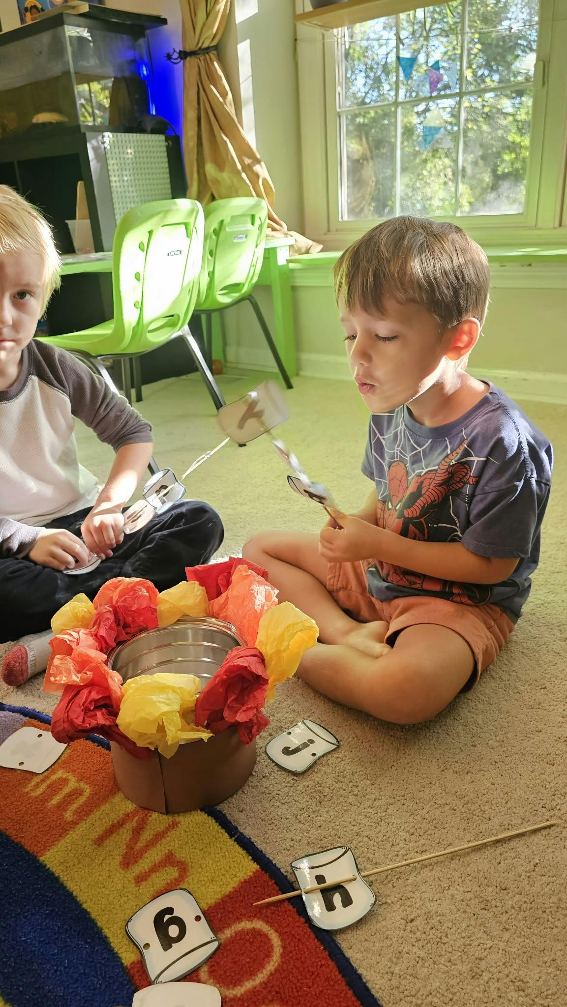 Two children playing with marshmallow-shaped number cards and a colorful pot