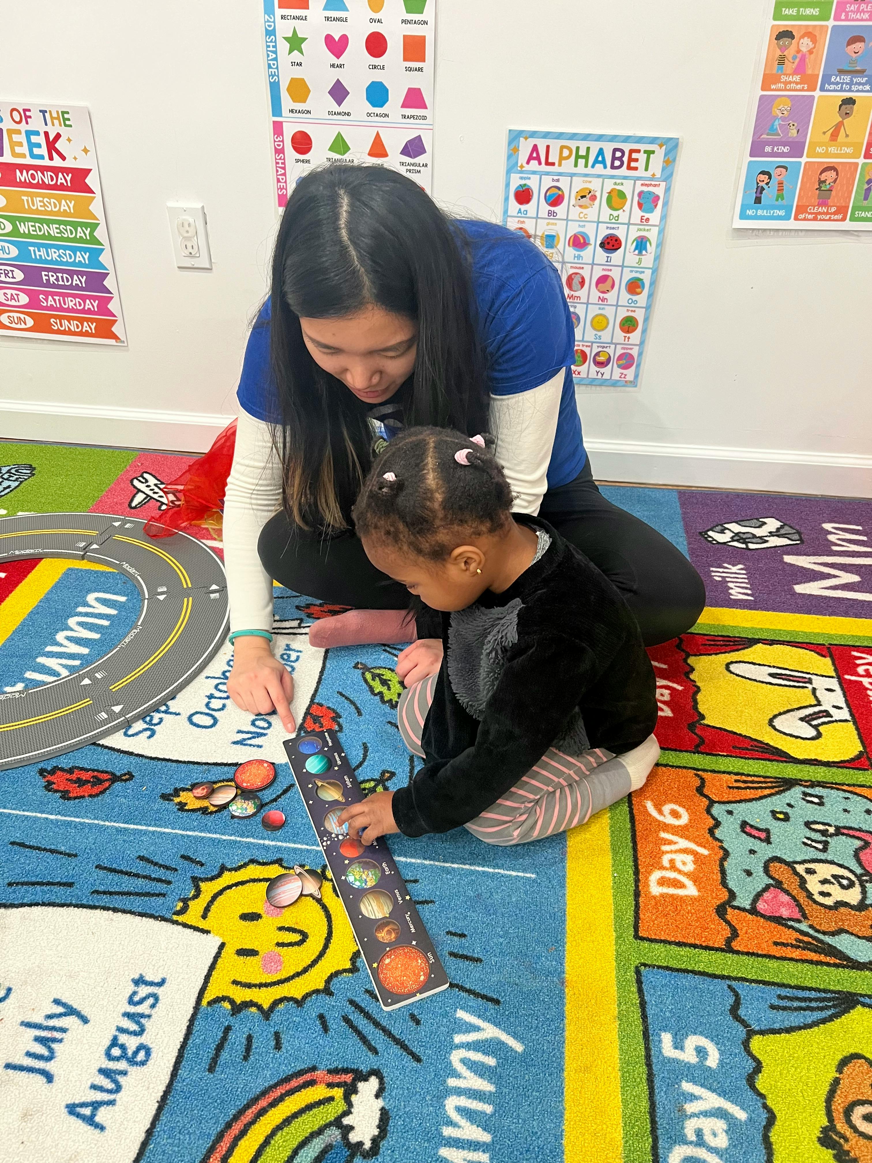 Adult and child on floor playing with a solar system toy