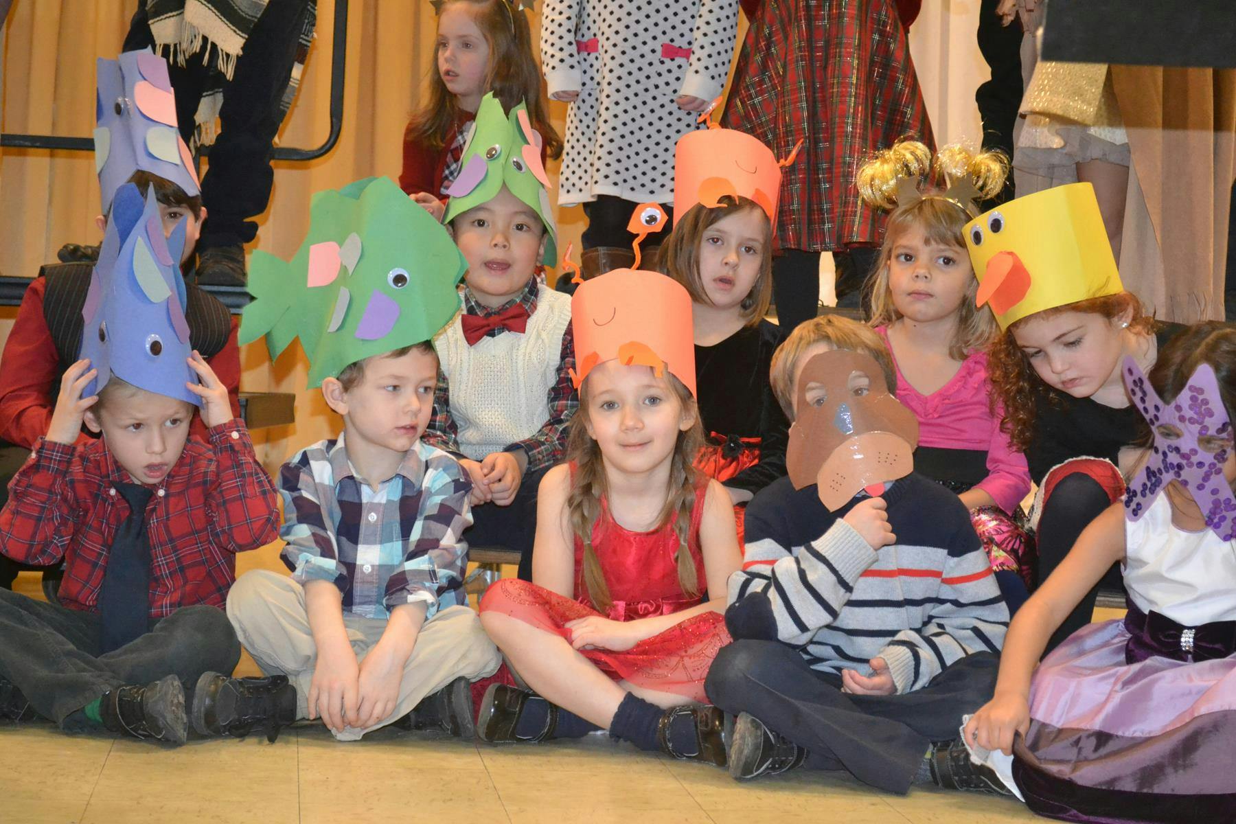 Children sitting on the floor wearing paper hats