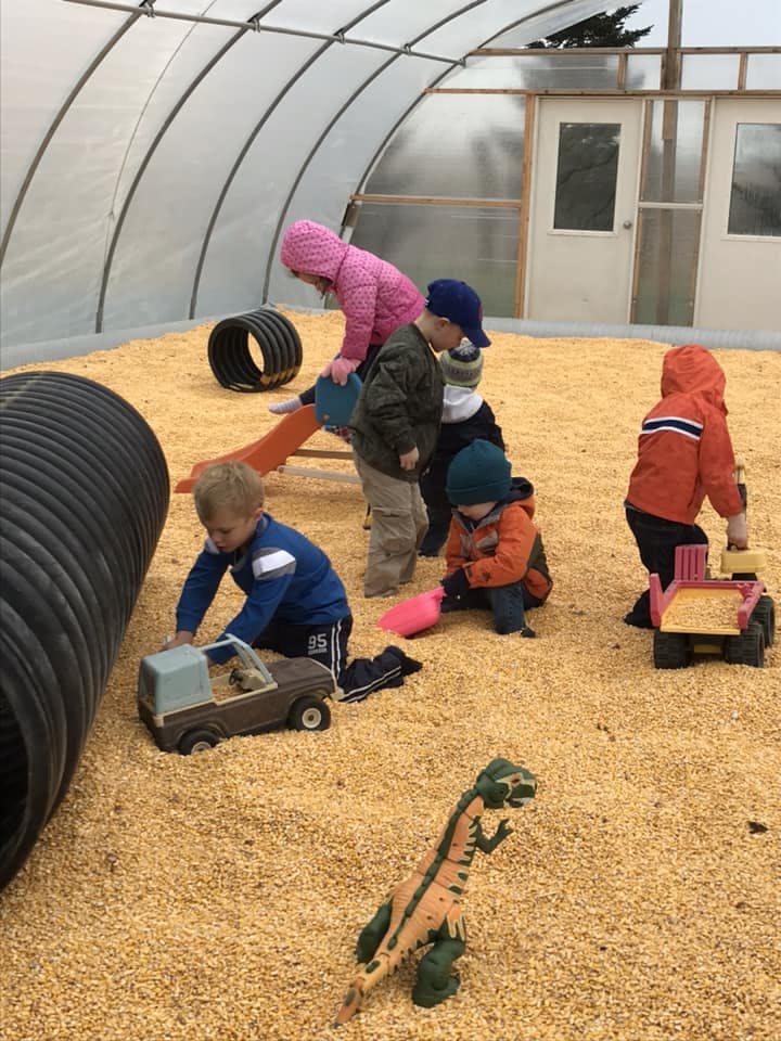 Children playing with toys in a large indoor sandbox