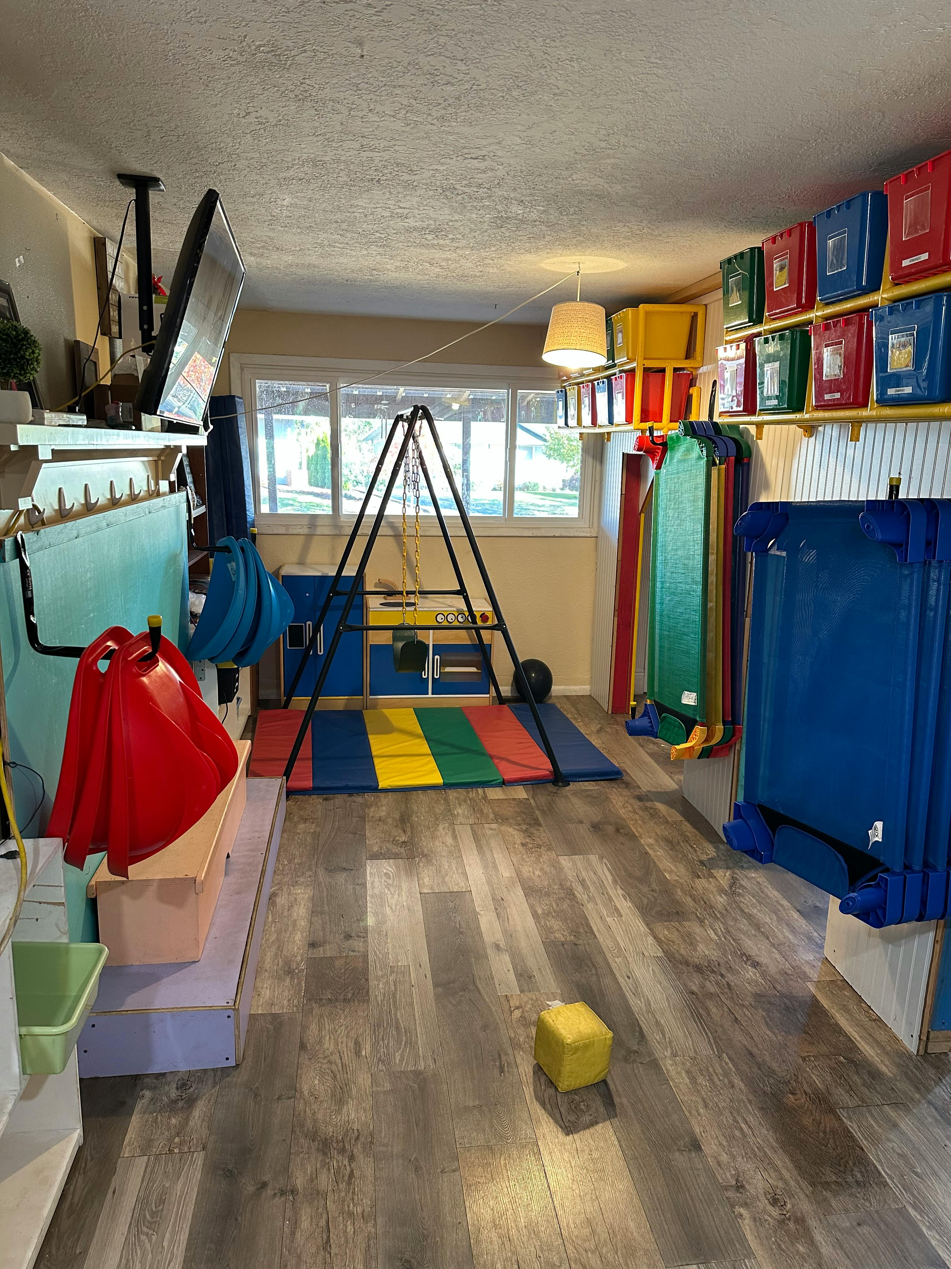 Indoor play area with a climbing frame, colorful mats, and storage bins