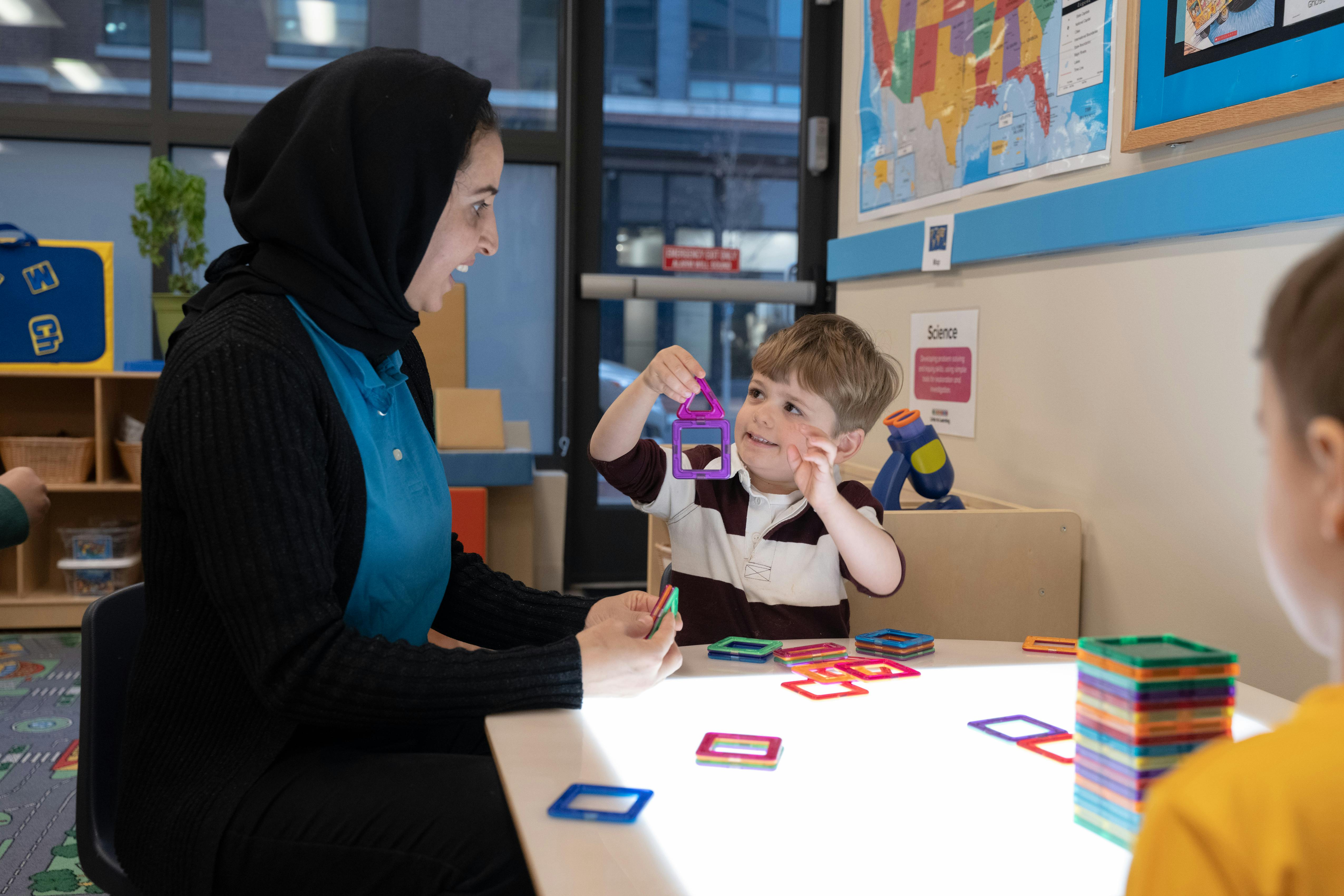 Person and child playing with colorful magnetic shapes at a table