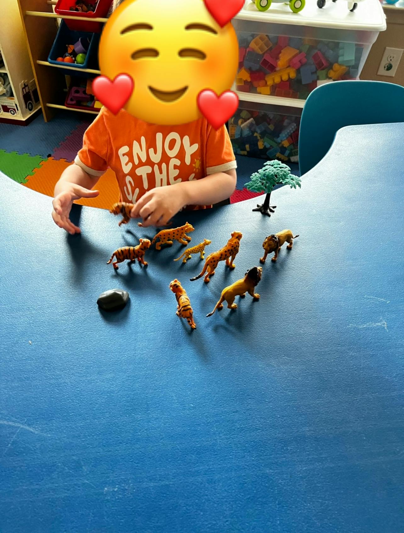 Child playing with animal figurines on a blue table