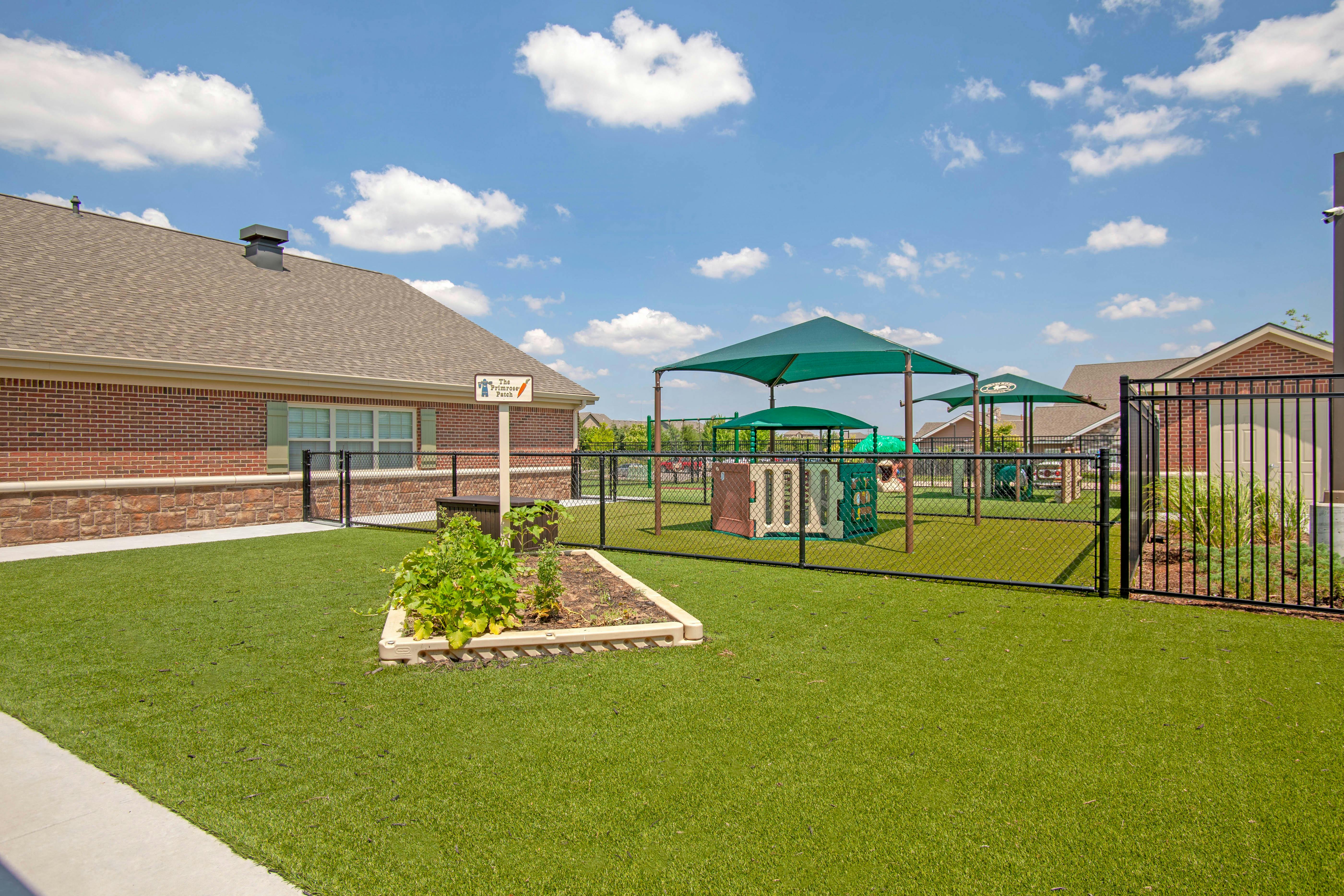 Outdoor playground with green turf and a garden box in the foreground