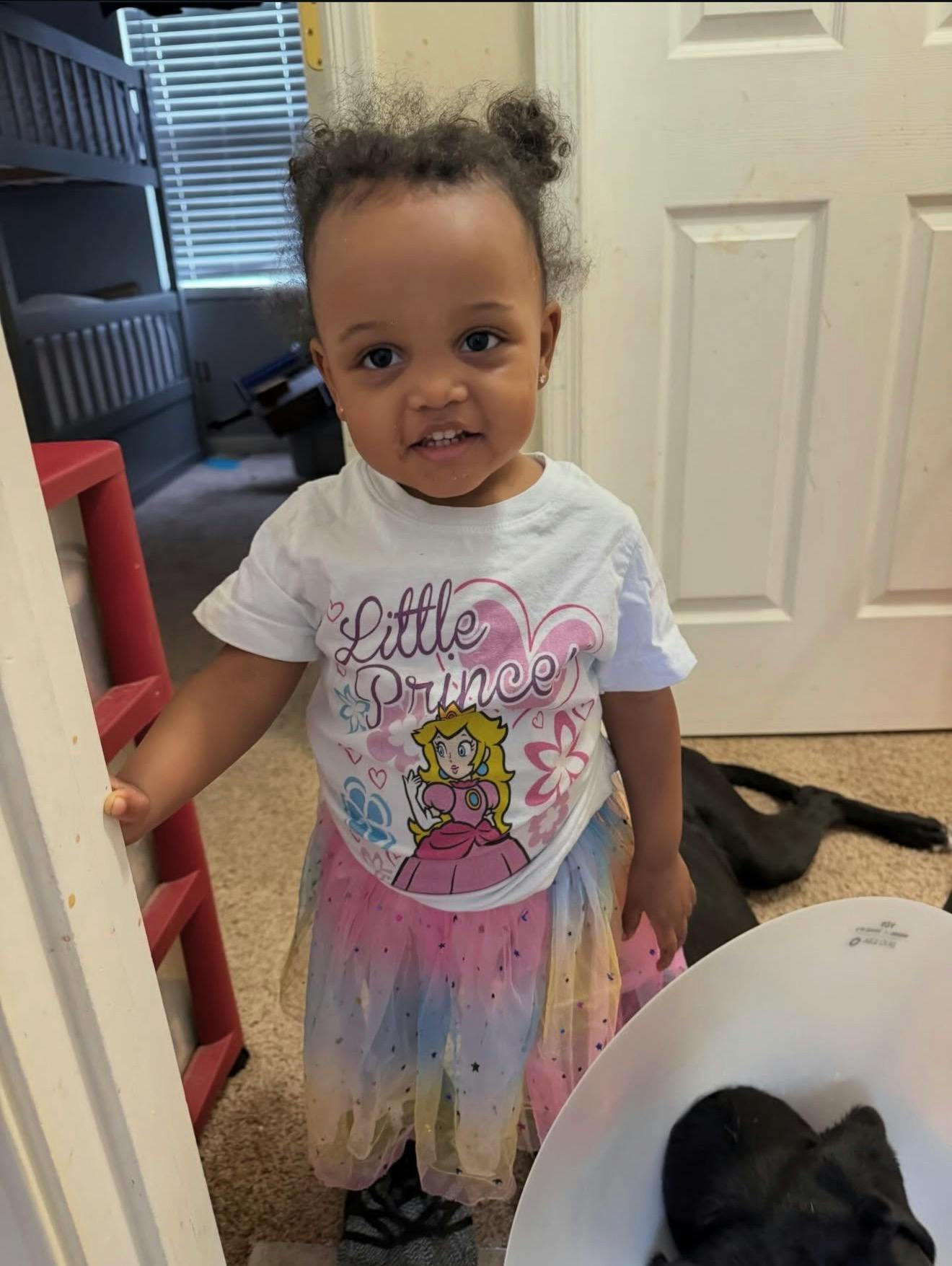 A small child wearing a graphic t-shirt and a colorful tutu