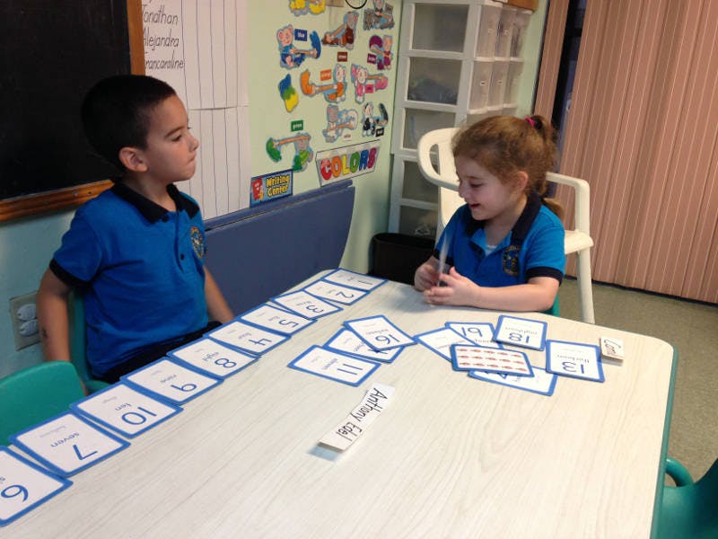 Two children at a table with number cards