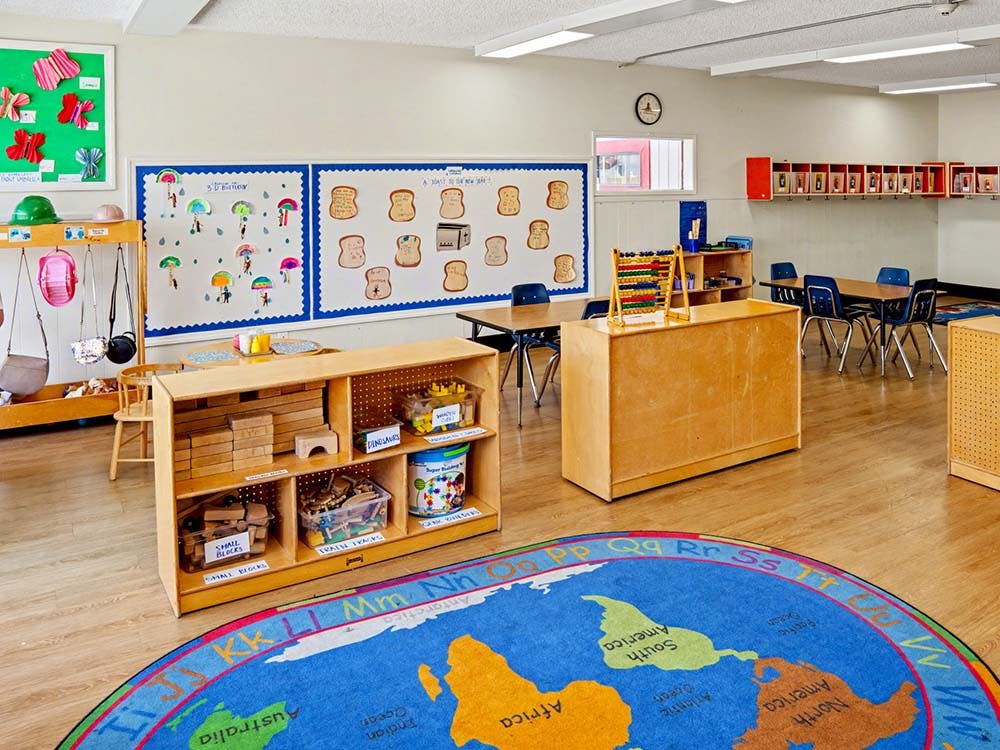 Classroom with play area, tables and chairs, and a world map rug