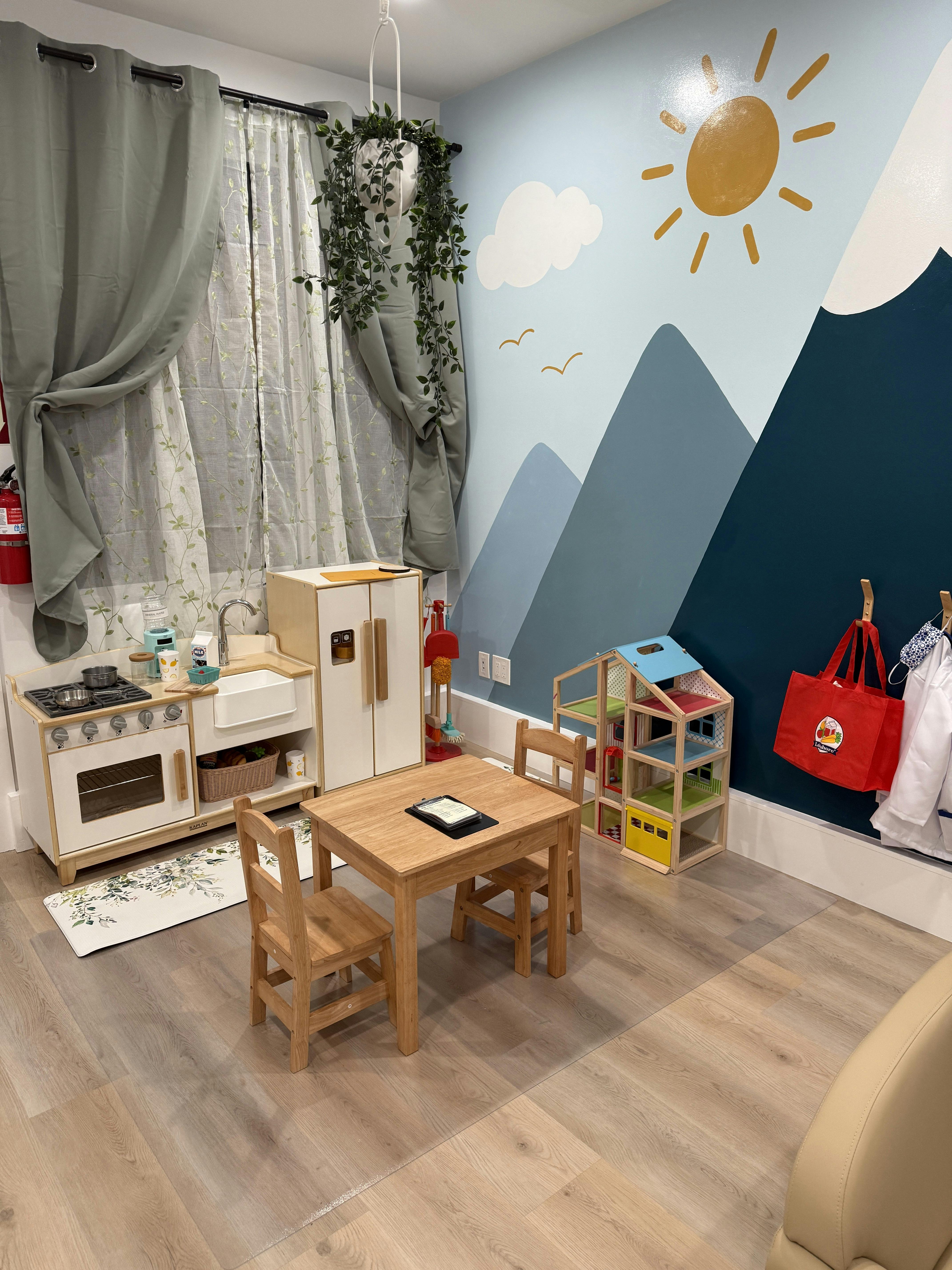 Playroom with toy kitchen, small table and chairs, and mountain mural