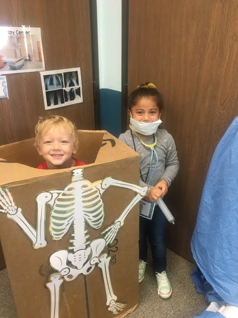 Child in a skeleton costume box and a child in a face mask and stethoscope