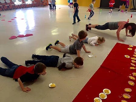 People and children doing push-ups and crawling on a floor