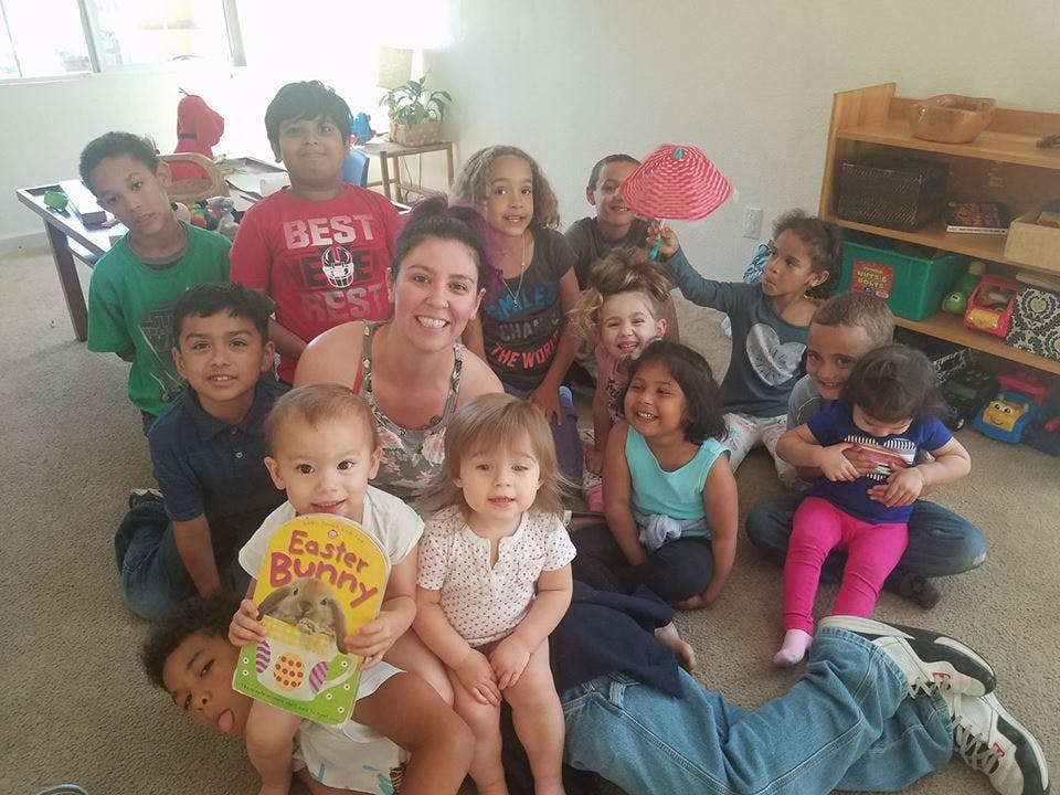 Person with a group of children, one child holding a book that says "Easter Bunny"