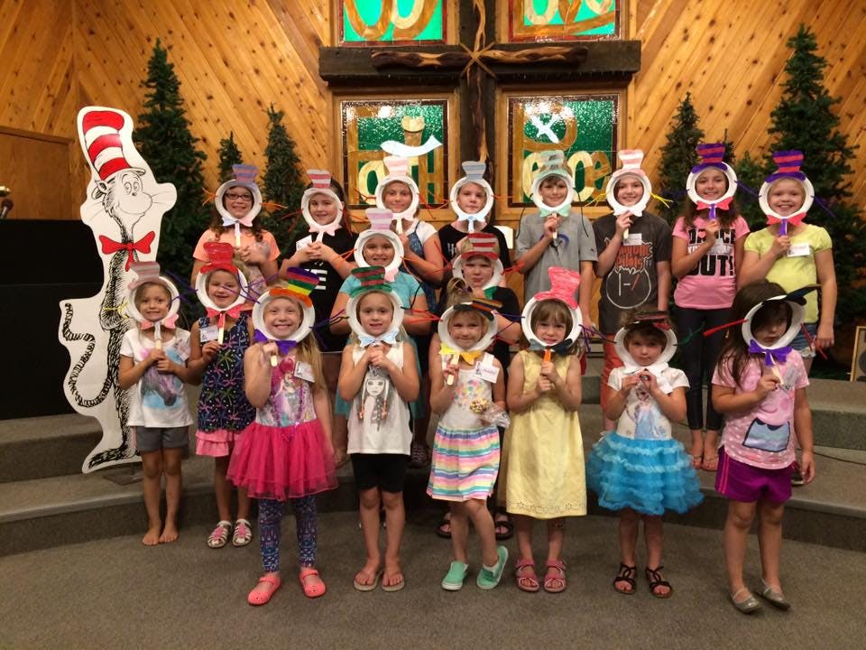 Group of children holding up paper cutouts of hats to their faces