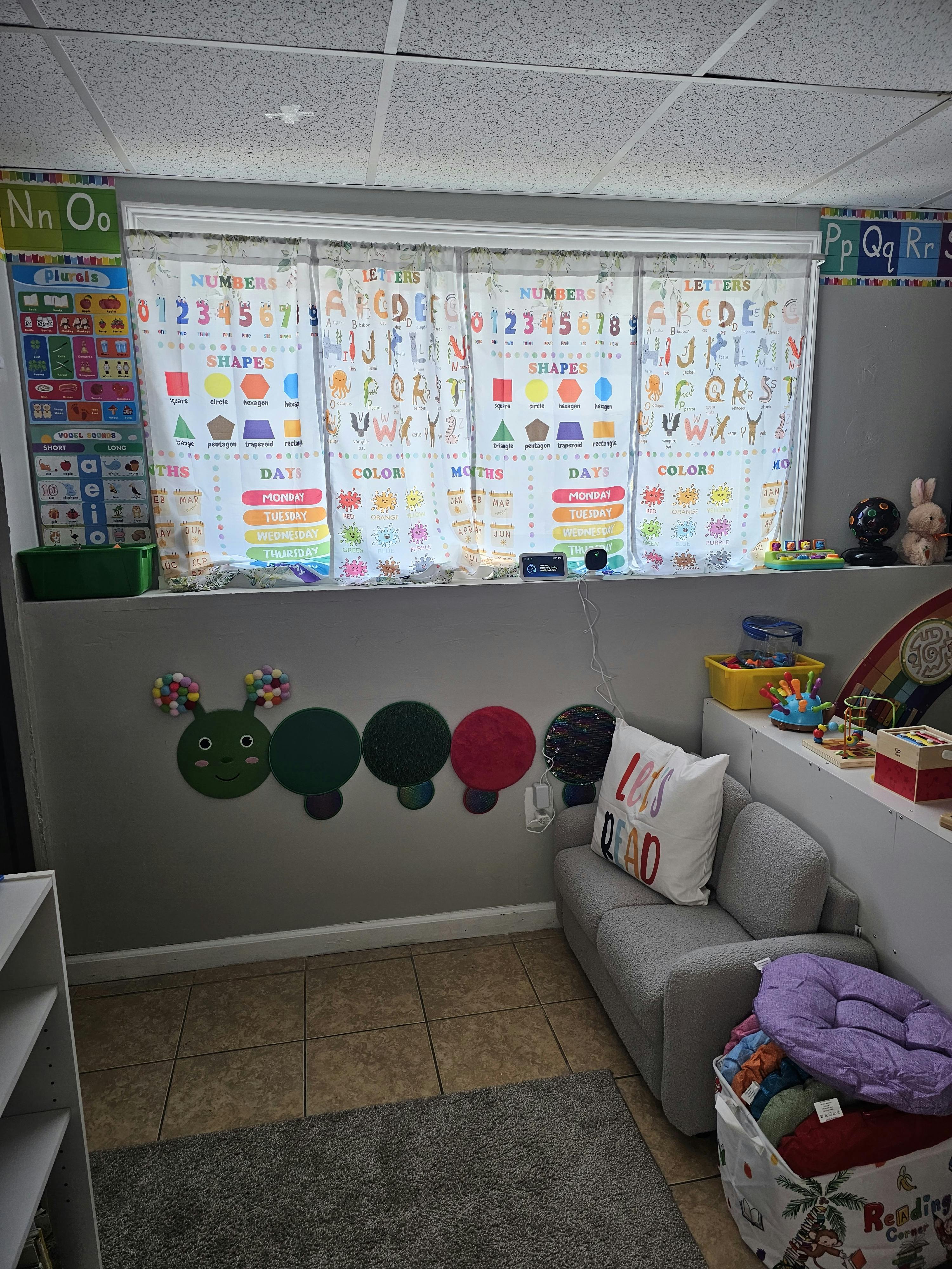 Classroom or play area with educational charts and a reading corner