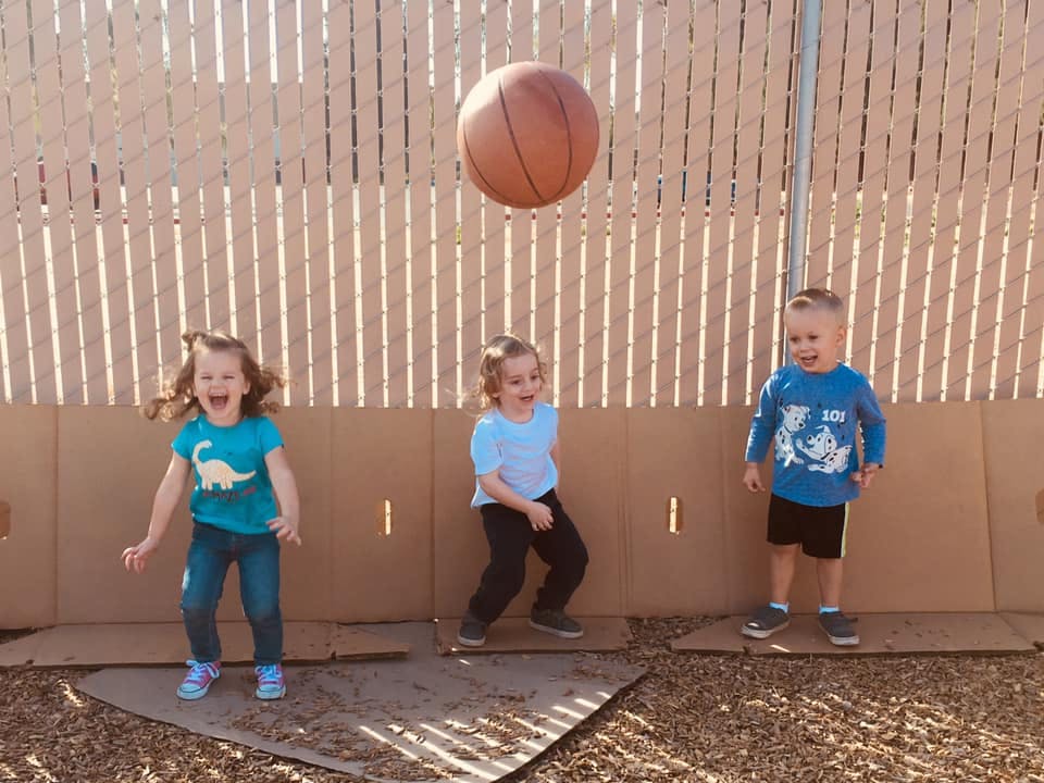 Three children playing with a basketball outdoors