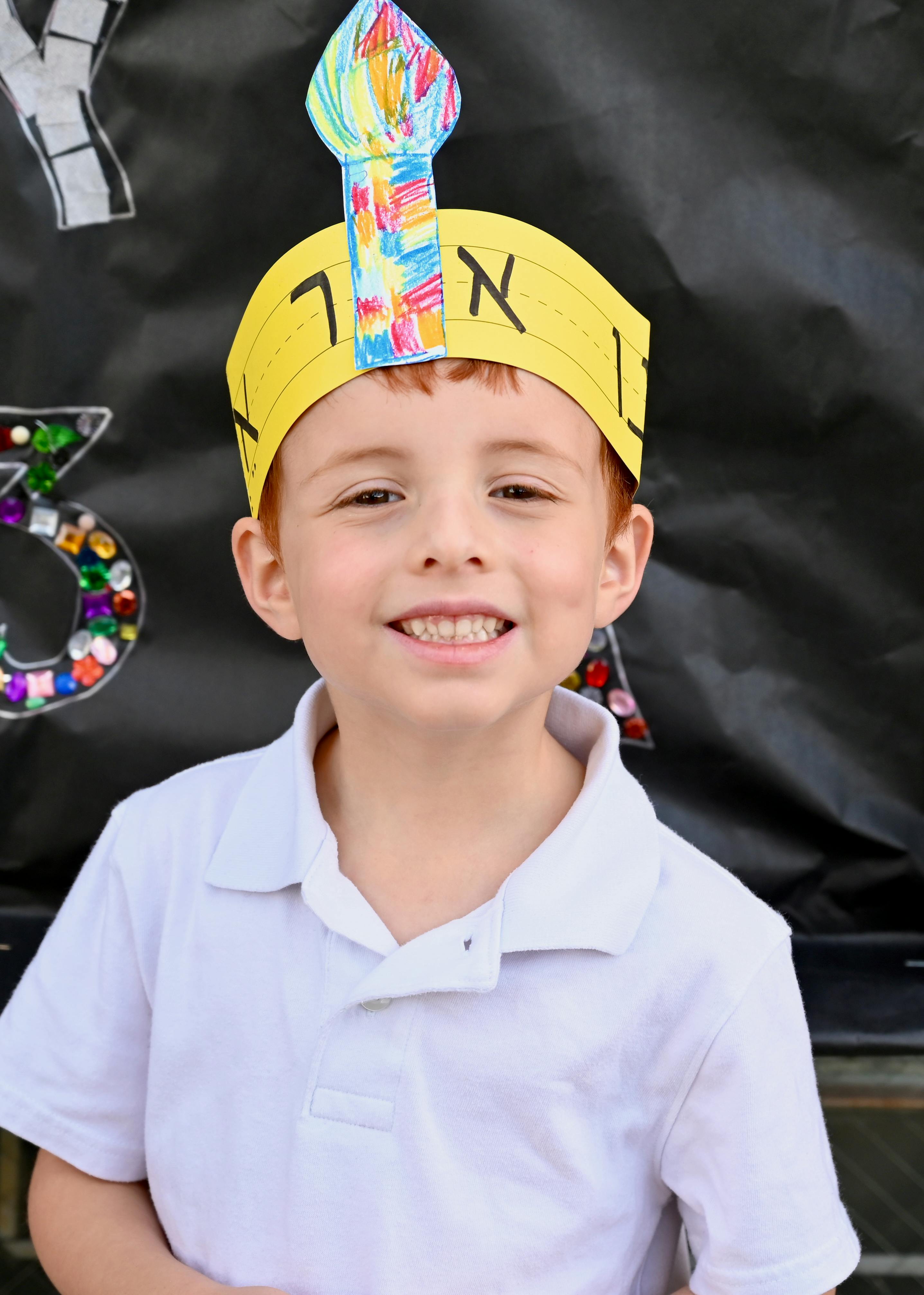 Child wearing a yellow paper crown with a colorful menorah