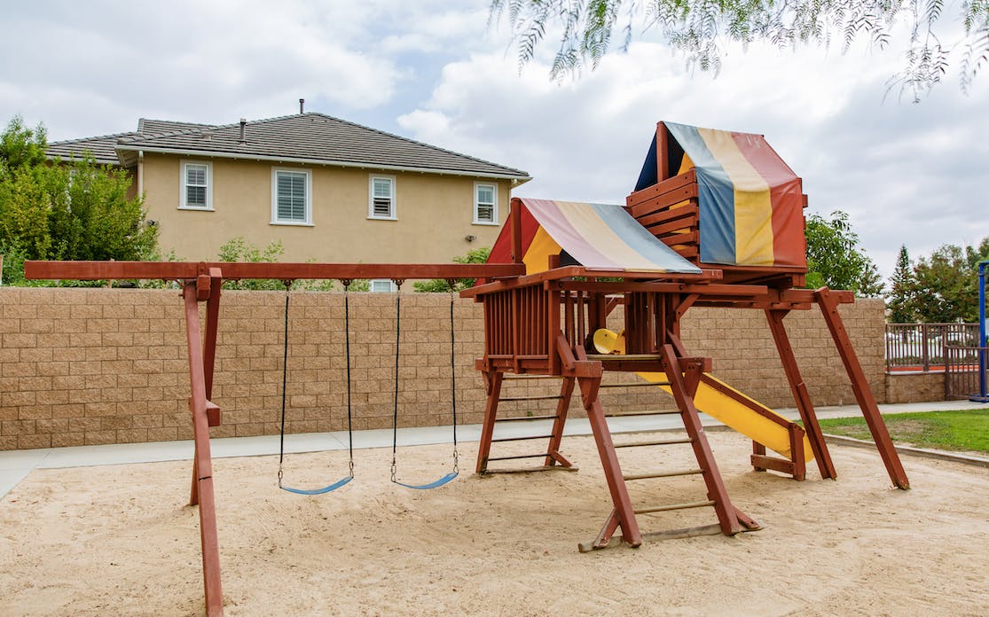 Wooden playground with swings and a colorful canopy