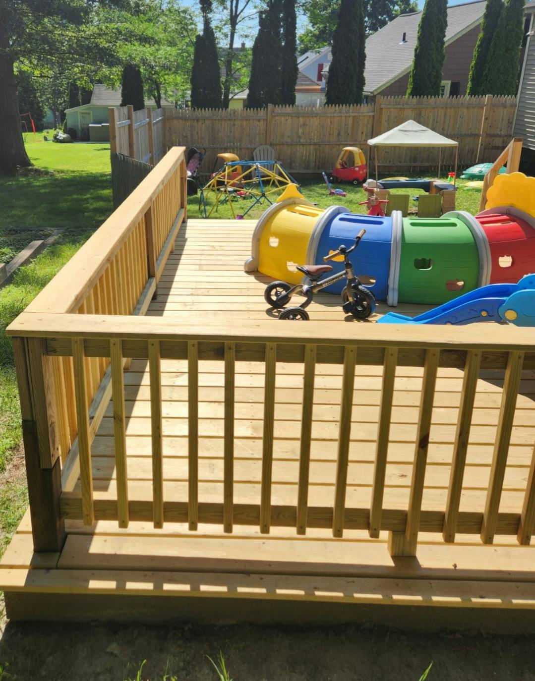 Wooden deck overlooking a backyard with colorful playground equipment