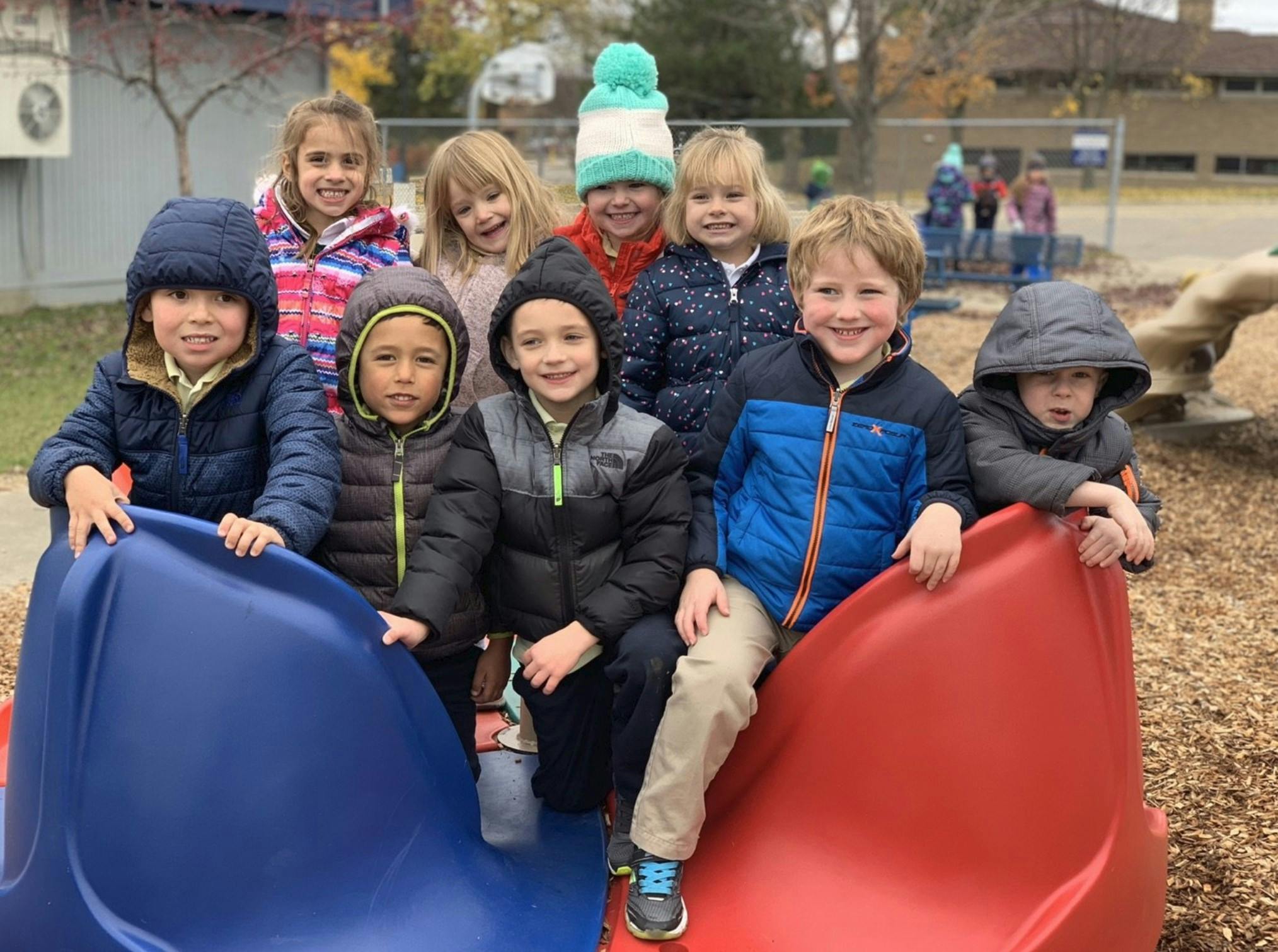 Group of children sitting on a red and blue playground slide