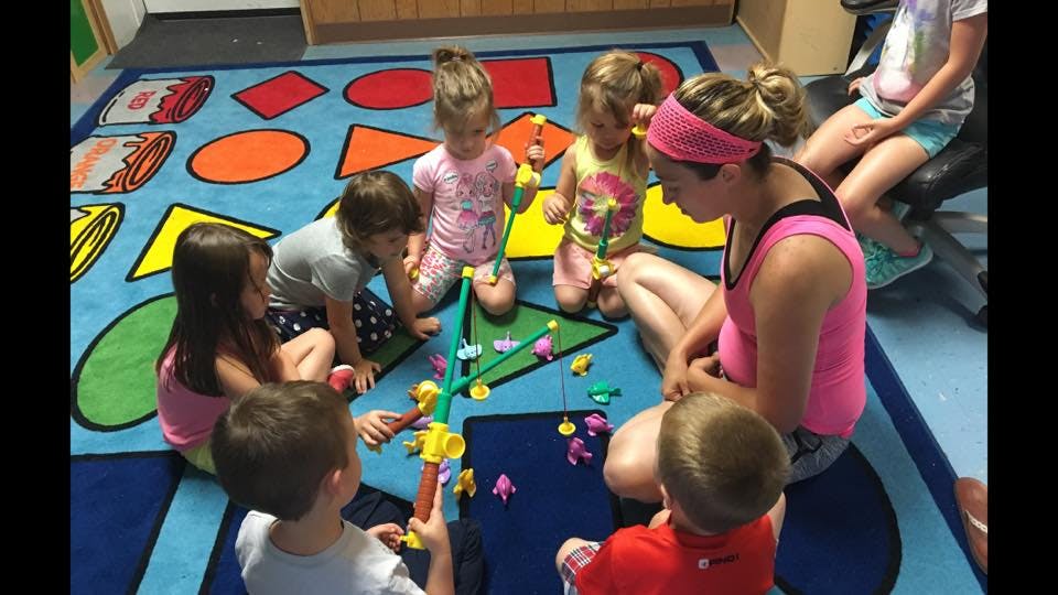 Adult and children playing with toys on a colorful rug