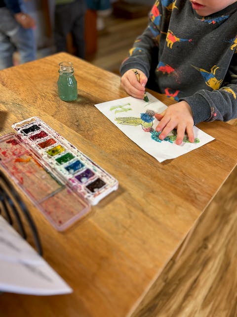Child painting at a wooden table with watercolors