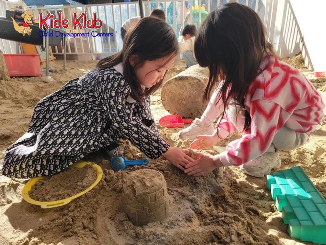 Children playing with sand and toys in a sandbox