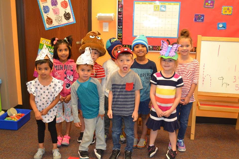 Group of children wearing hats standing in a classroom
