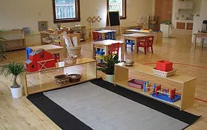 Classroom with small tables and shelves with learning materials