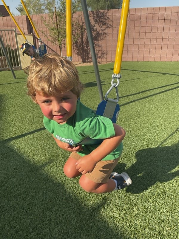 Child smiling while sitting in a swing on a playground