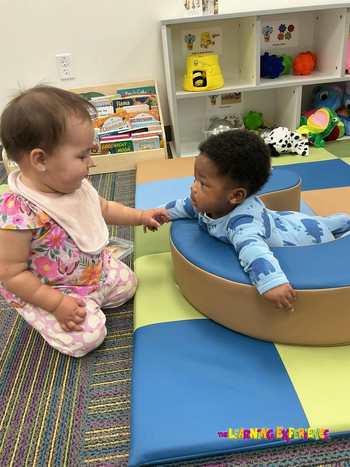 Two children interacting on soft mats in a classroom