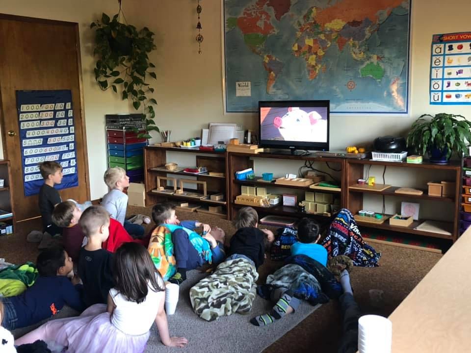 Children sitting on the floor watching television in a classroom