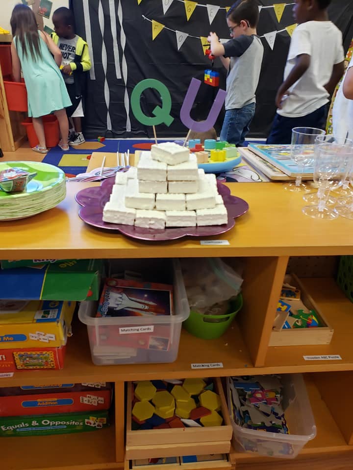 Children in a classroom with a table of snacks and toys