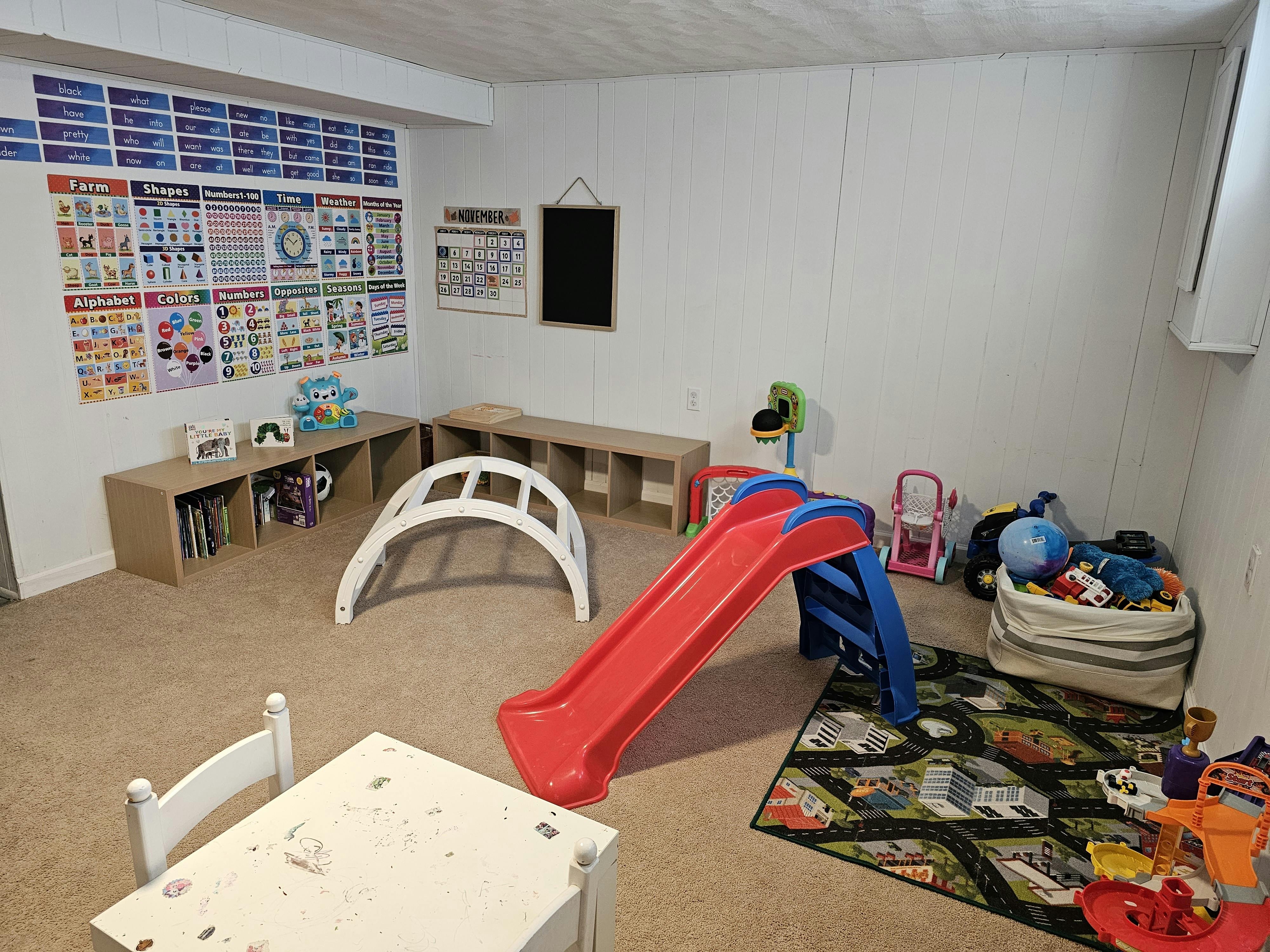 Indoor play area with a red slide, climbing dome, and educational posters
