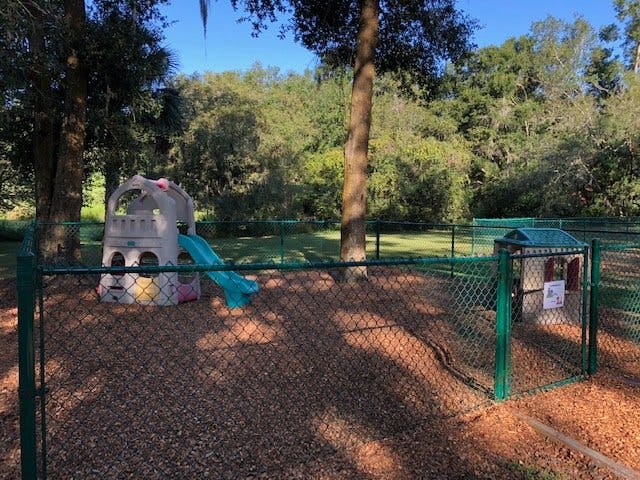 Playground with a small slide and playhouse inside a fenced area